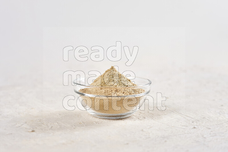 A glass bowl full of ground ginger powder on white background