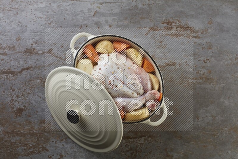 whole raw chicken on in a white ceramic pot direct on a rustic grey background