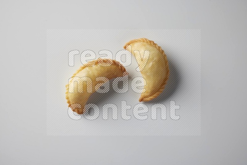 Two fried sambosa from a top angle on a white background