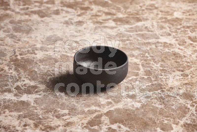 A black pottery bowl on beige marble background