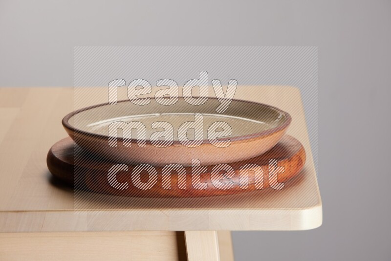 multi-colored pottery Plate placed on a dark colored wooden tray on the edge of wooden table