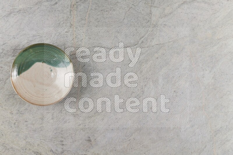 A decorative pottery plate on grey marble background