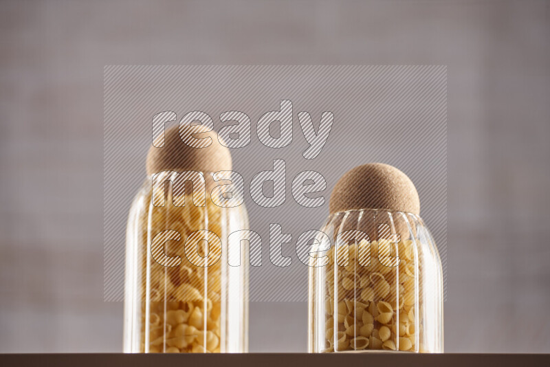 Raw pasta in glass jars on beige background