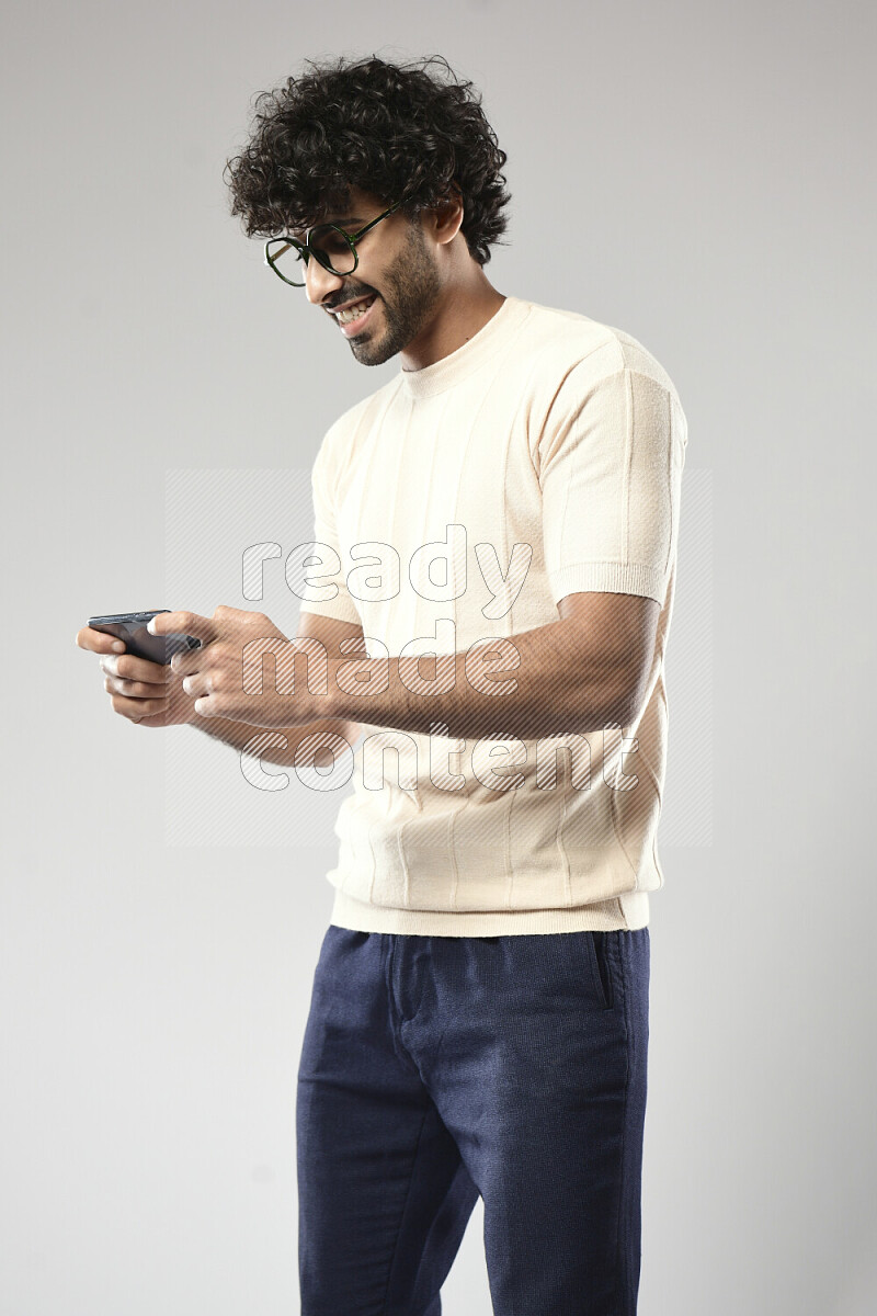A man wearing casual standing and gaming on the phone on white background