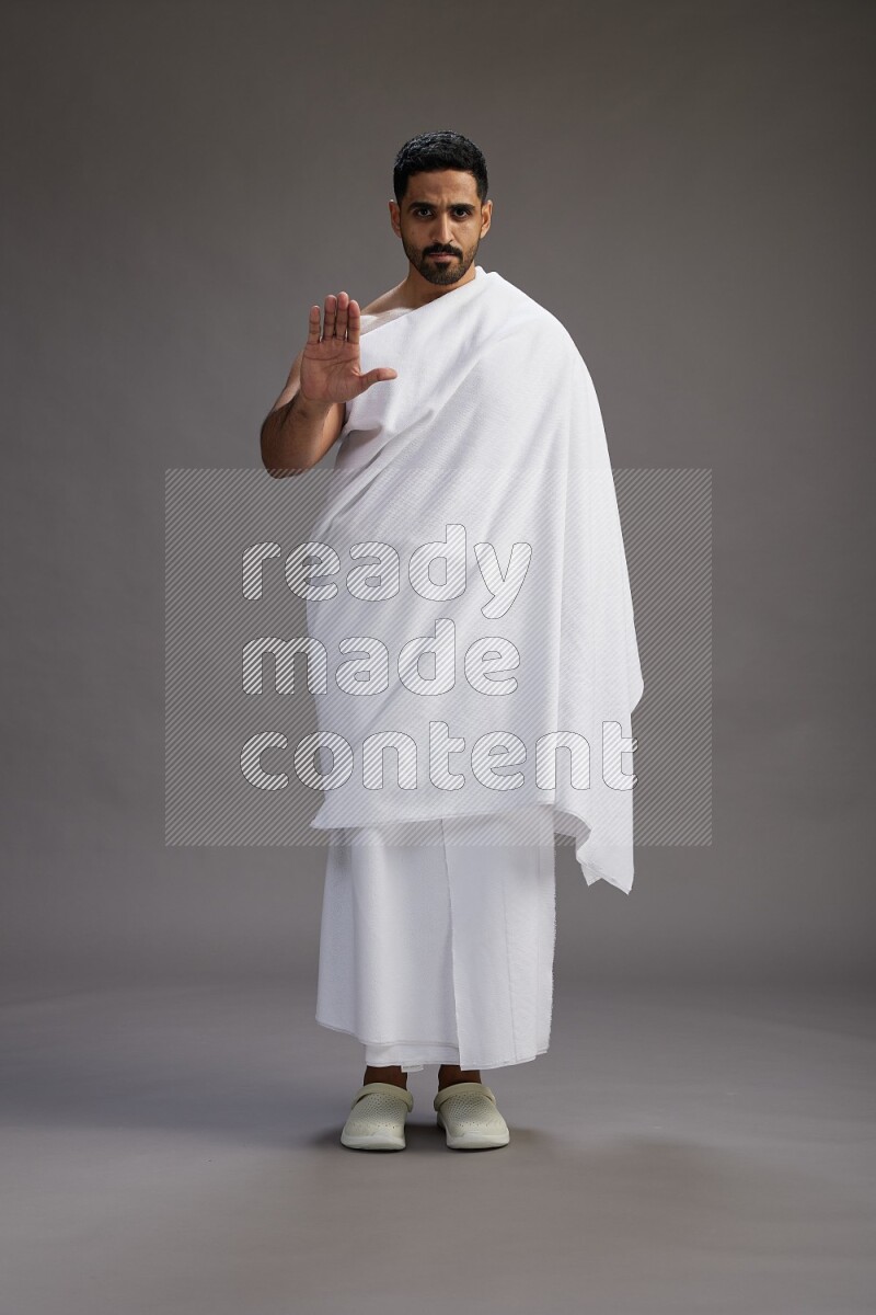 A man wearing Ehram Standing Interacting with the camera on gray background