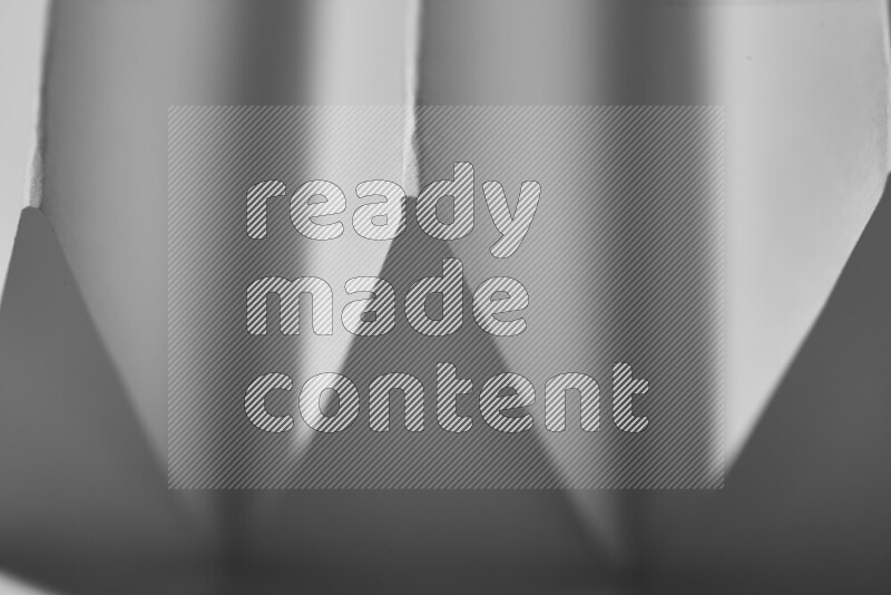 صورة مجردة مقربة تظهر طيات ورقية هندسية حادة بتدرجات اللون الرمادي