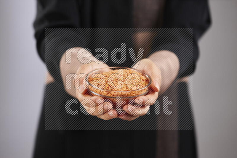 Woman in abaya holding different kinds of legumes in different positions