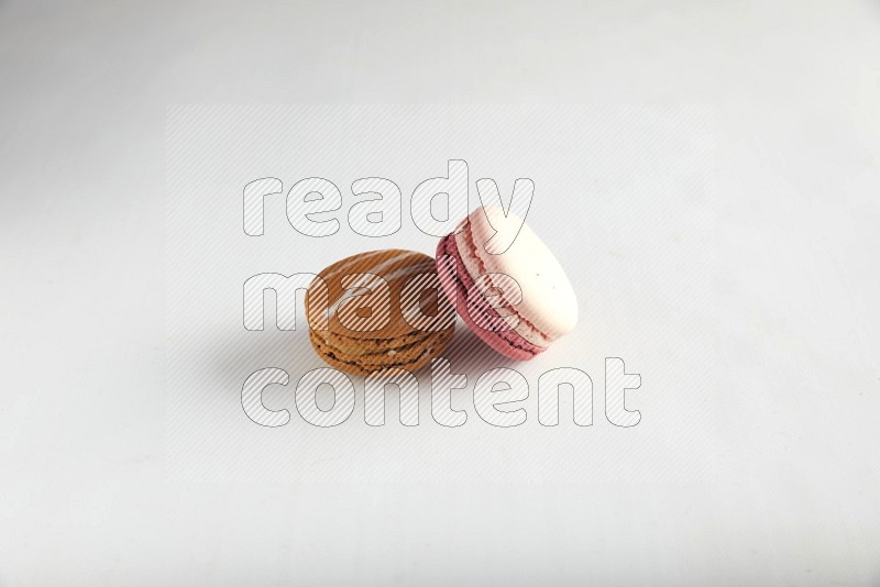 45º Shot of of two assorted Brown Irish Cream, and Pink Litchi Raspberry macarons on white background