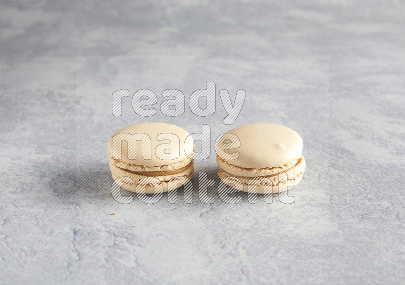 45º Shot of two white marbleCaramel fleur de sel macarons  on white  marble background