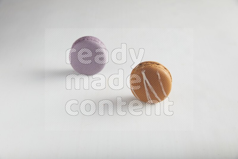 45º Shot of of two assorted Brown Irish Cream, and Purple Blueberry macarons on white background