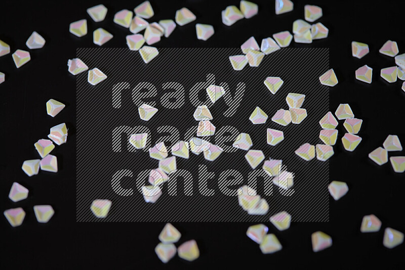Colorful plastic shards for decoration scattered on a black background