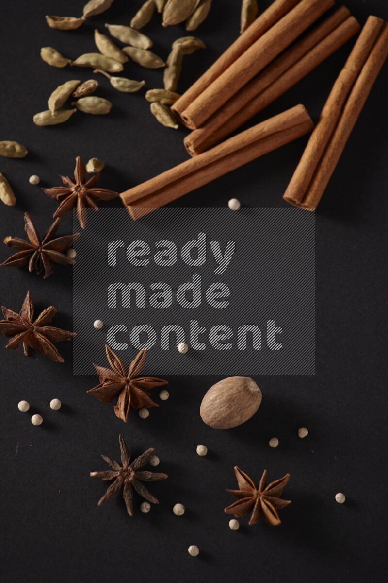 Cinnamon sticks, cardamom, star anise, nutmeg and white peppers on a black background