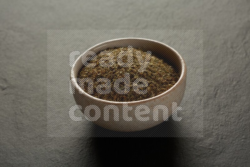 multi color round sauce bowl filled with herbs on grey textured countertop