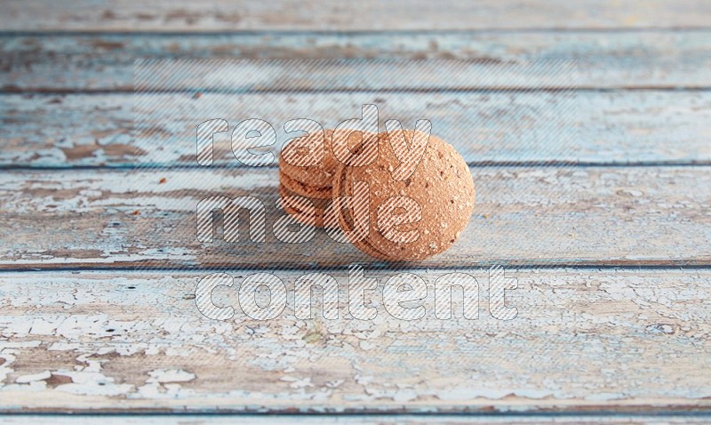 45º Shot of two Brown Hazelnuts macarons on light blue wooden background