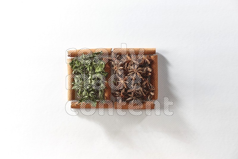 2 squares of cinnamon sticks full of star anise and dried mint leaves on white flooring
