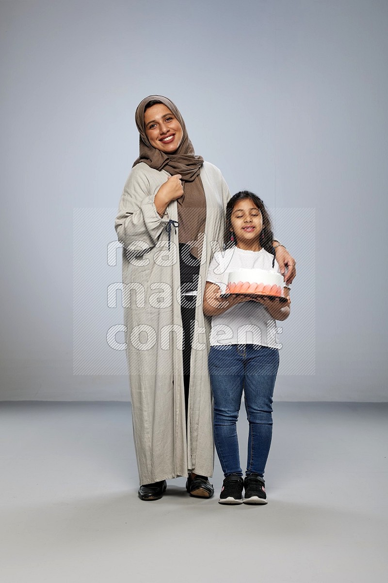 A girl giving a cake to her mother on gray background