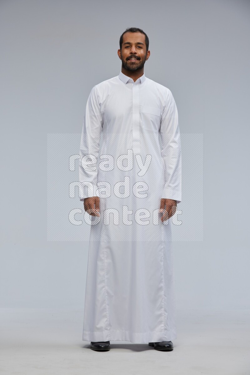 Saudi man Wearing Thob standing interacting with the camera on Gray background