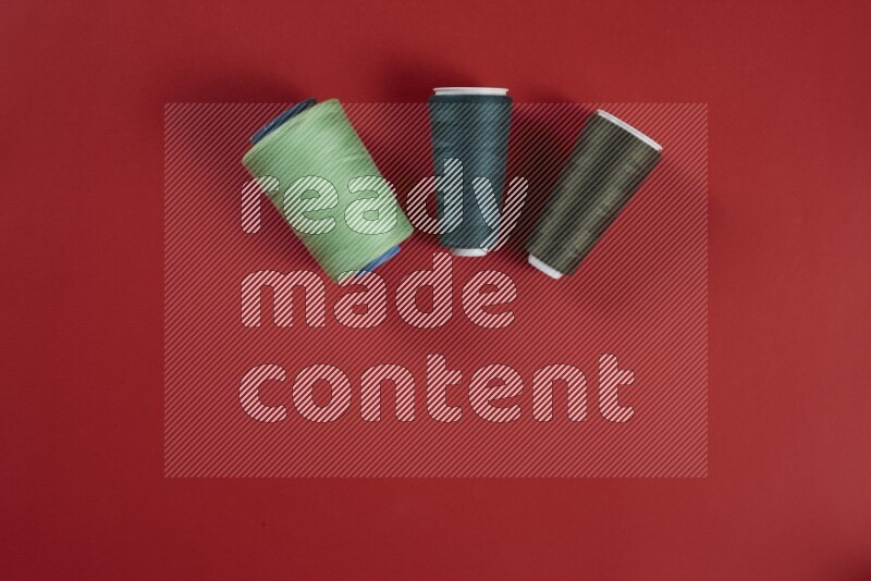 A green and red collection of sewing and tailoring tools arranged on a red background