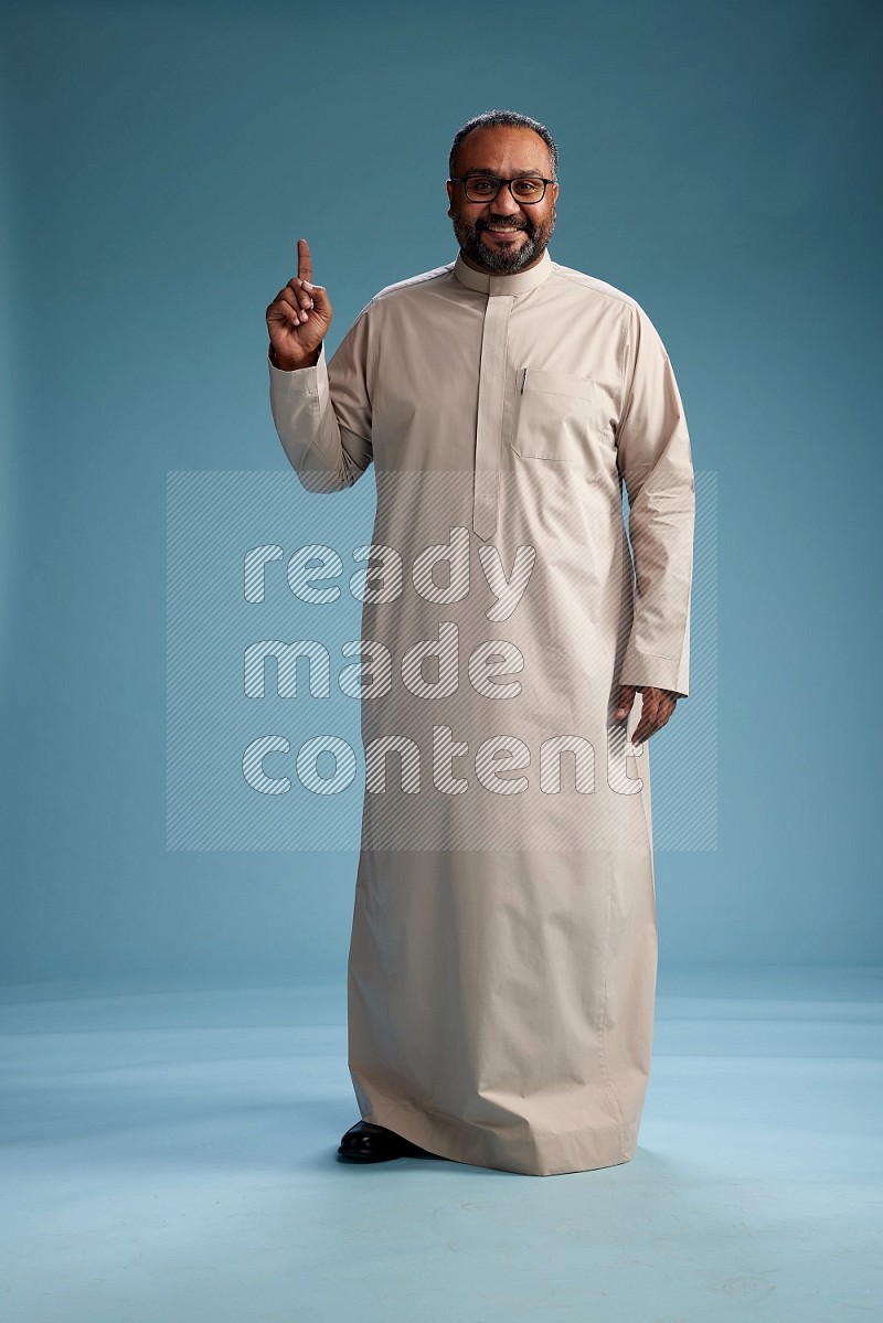 Saudi Man without shimag Standing Interacting with the camera on blue background