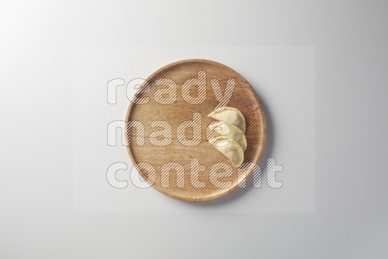 Three Sambosas on a wooden round plate on a white background