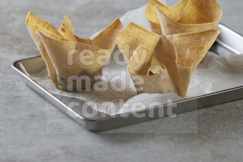 wonton cups on parchment paper in stainless tray on grey textured counter top