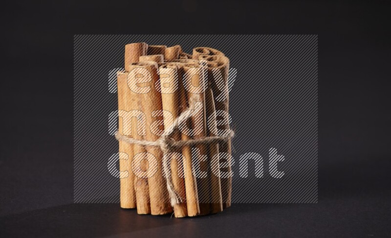 A bounded stack of cinnamon sticks on black background