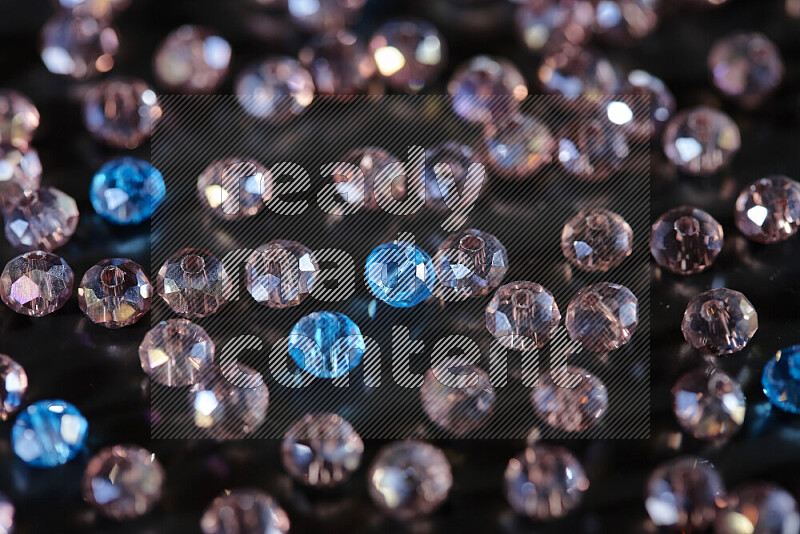 Rose and blue transparent crystal beads scattered on a black background
