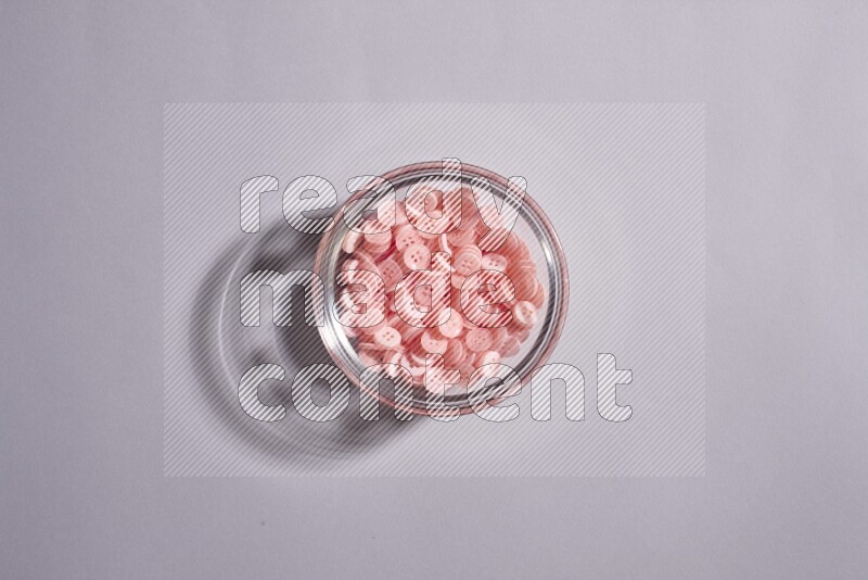 Colored buttons in a glass bowl on grey background