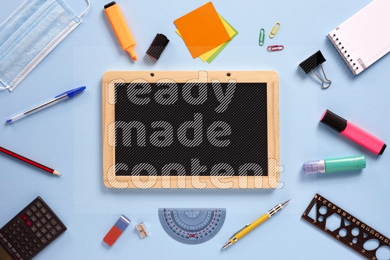 A black board with school supplies on blue background (back to school)