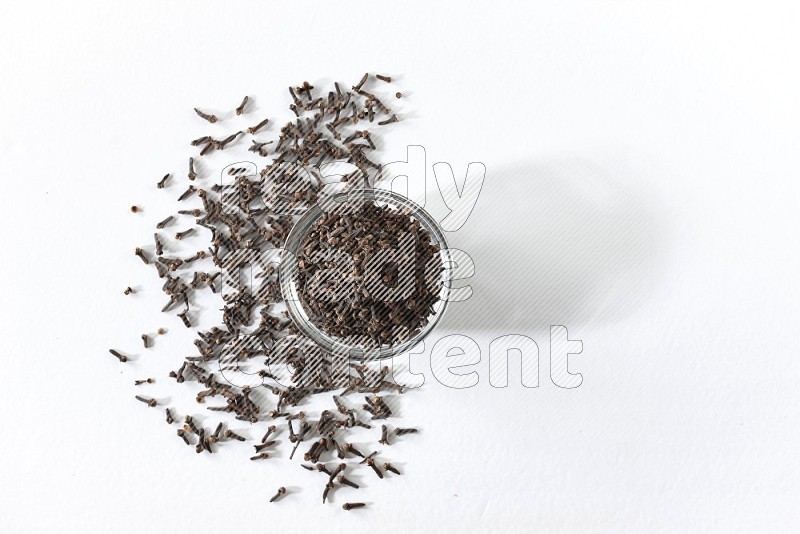 A glass bowl full of cloves on a white flooring