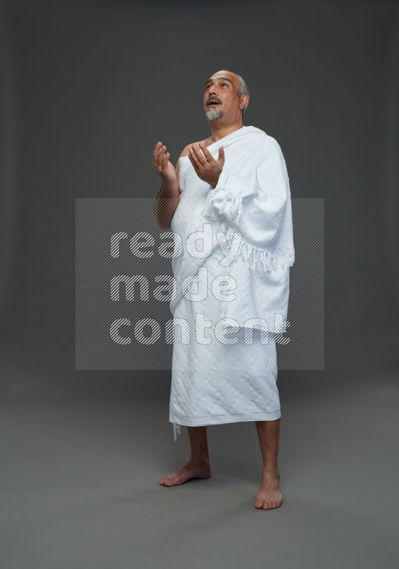 A man wearing Ehram Standing dua'a on gray background