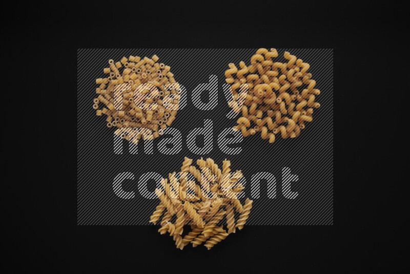 Different pasta types in bunches on black background