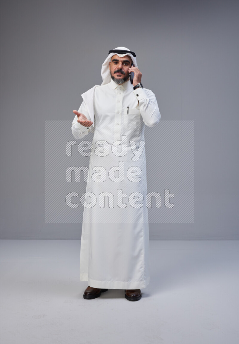 رجل سعودي يرتدي ثوب وشماغ ابيض يتحدث بهاتفه الجوال