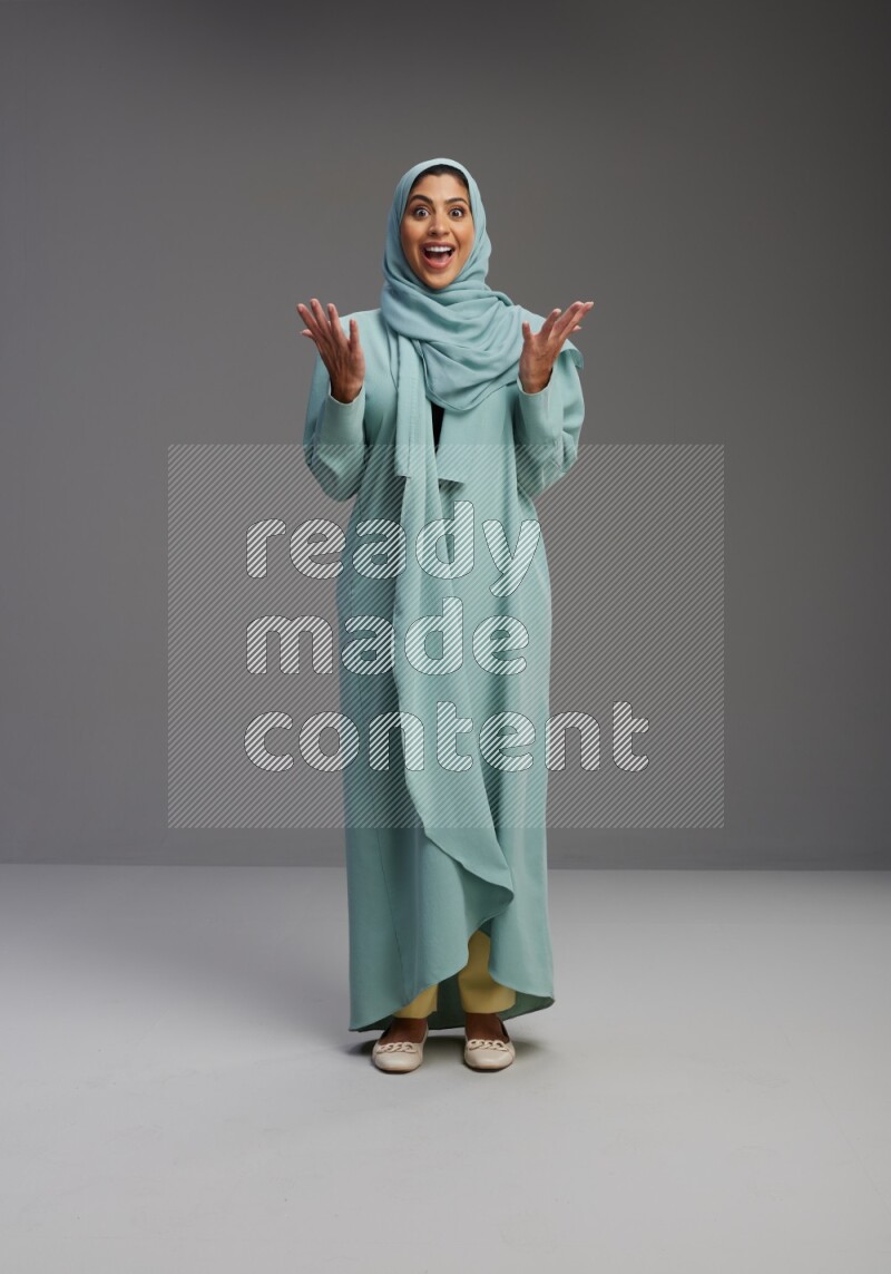 Saudi Woman wearing Abaya standing interacting with the camera on Gray background