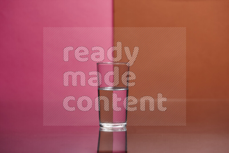 The image features a clear glassware filled with water, set against pink and dark orange background