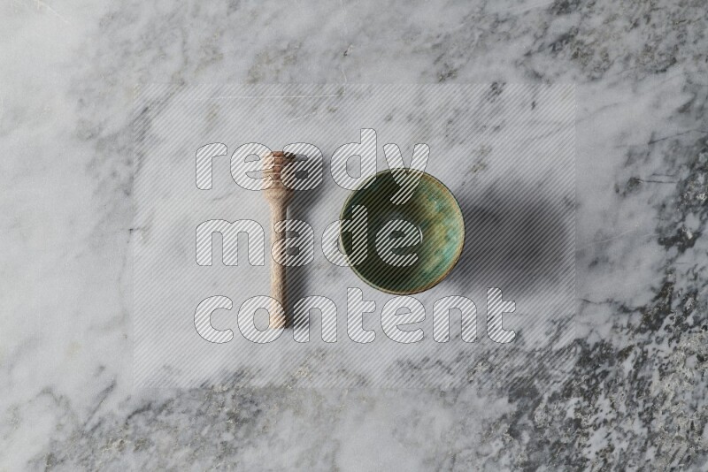 Multicolored pottery bowl with wooden honey dipper on the side on grey marble background