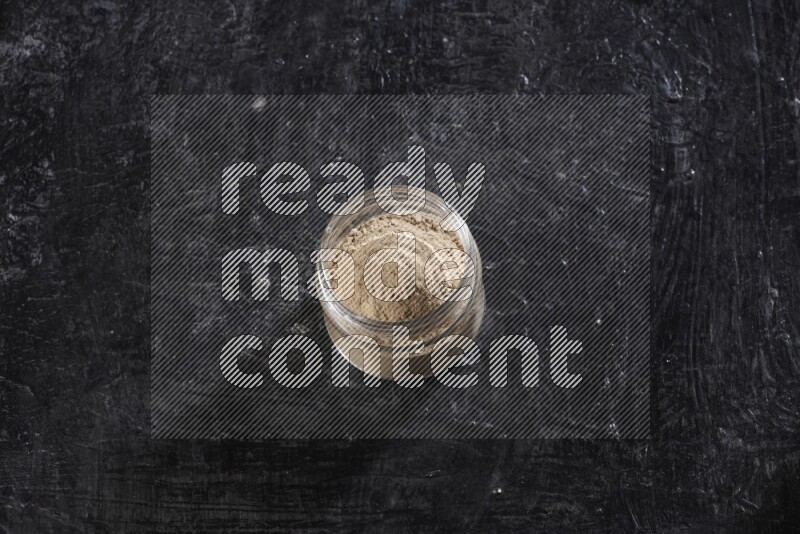 وعاء زجاجي ممتلئ ببودرة الثوم علي خلفية سوداء