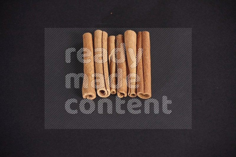 Cinnamon sticks stacked on black flooring