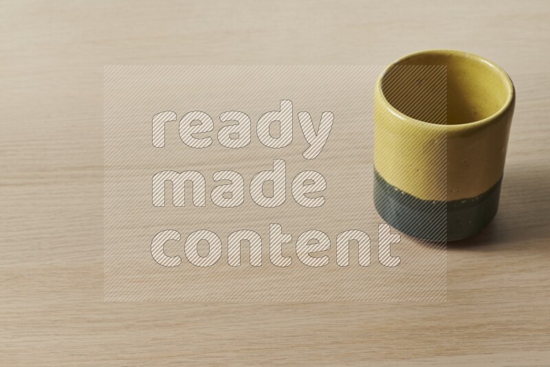 A multicolored pottery cup on light wooden background