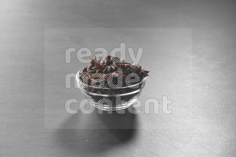 A glass bowl full of star anise on black flooring