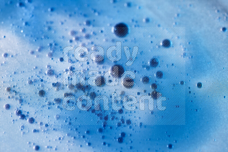 Close-ups of abstract blue watercolor drops on oil Surface on blue background