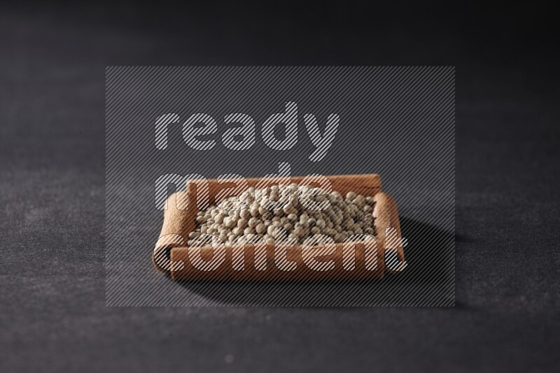 A single square of cinnamon sticks full of white pepper on black flooring