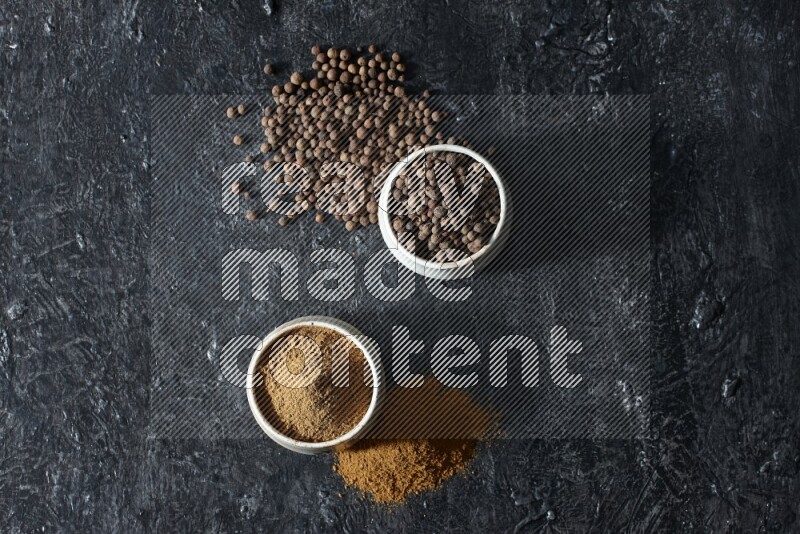 وعاءان بيج، أحدهما ممتلئ ببودرة بهار الفلفل الحلو والآخر بالحبوب وكلاهما متناثران على خلفية سوداء