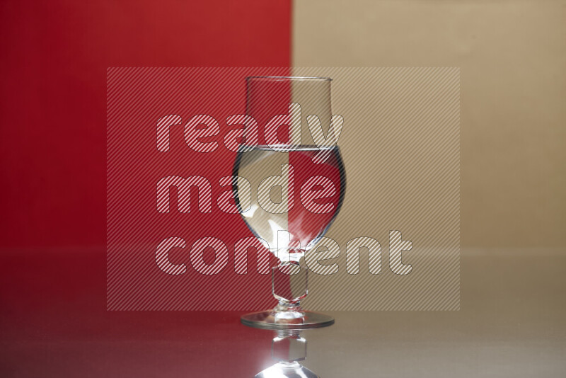 The image features a clear glassware filled with water, set against red and beige background