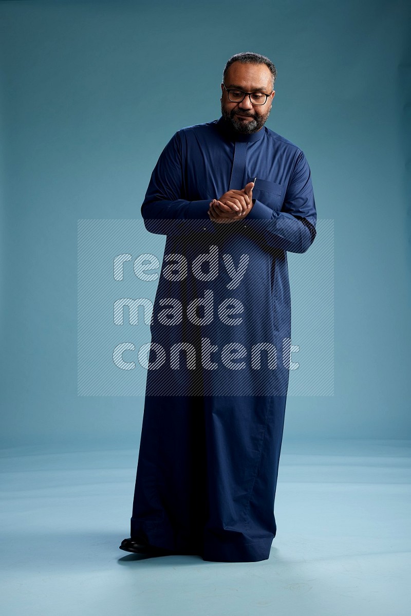 Saudi Man without shimag Standing Interacting with the camera on blue background