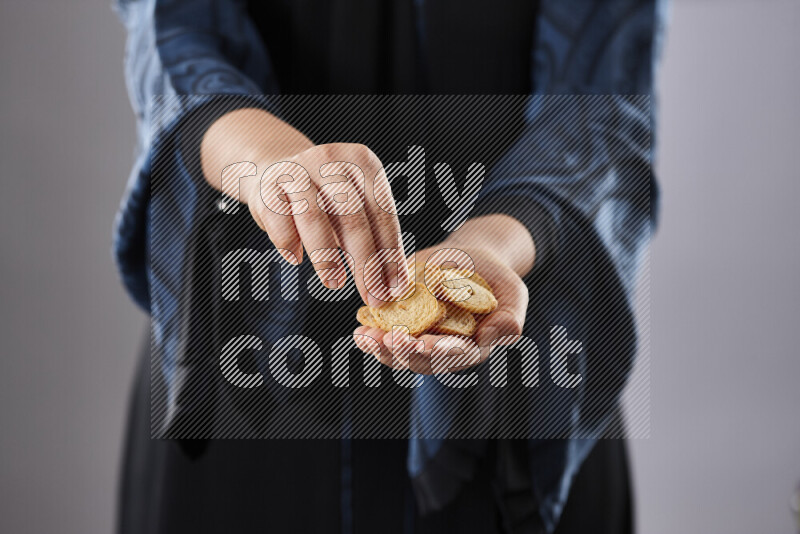 Woman in abaya holding different kinds of snacks in different positions