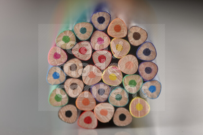An array of colored pencils on grey background