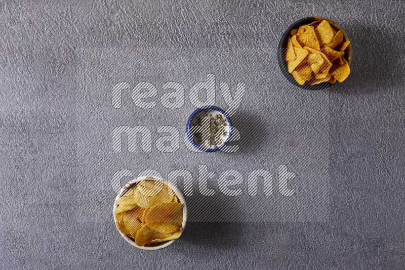 Assorted snacks in pottery bowls on grey background