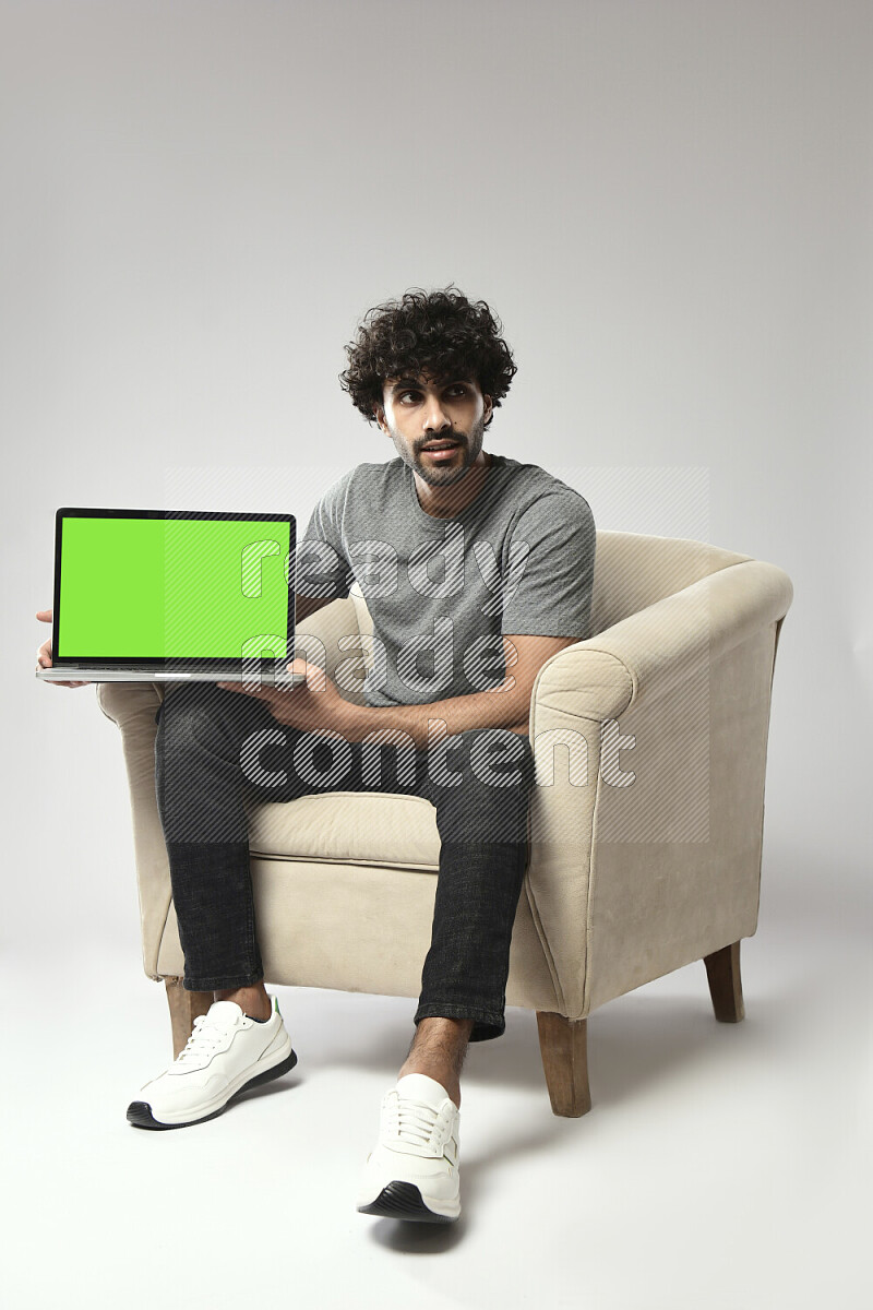 A man wearing casual sitting on a chair showing a laptop screen on white background