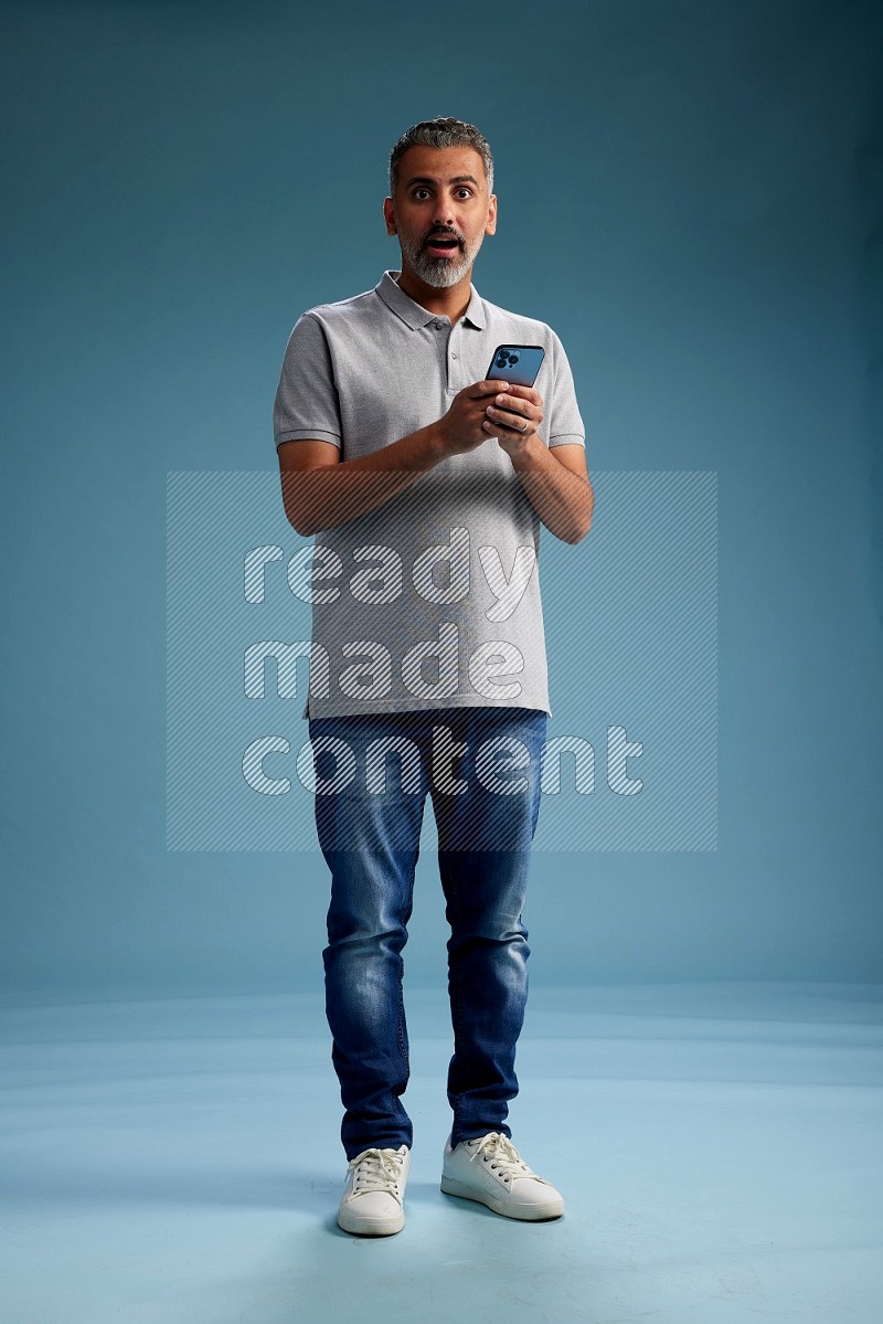 Man Standing texting on phone on blue background